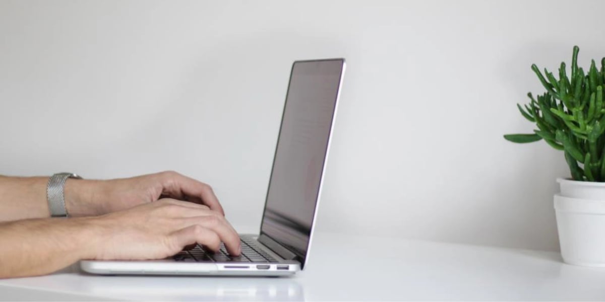 A hand typing on a laptop