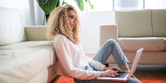 A student sitting on the floor and typing on a laptop