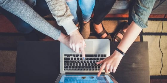 Studierende zeigen auf einen Laptop